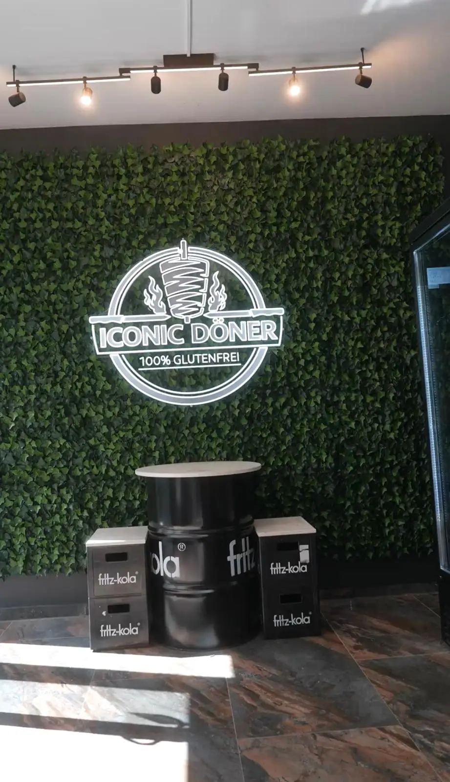Die Pflanzenwand mit dem leuchtenden Iconic-Döner-Logo im Laden