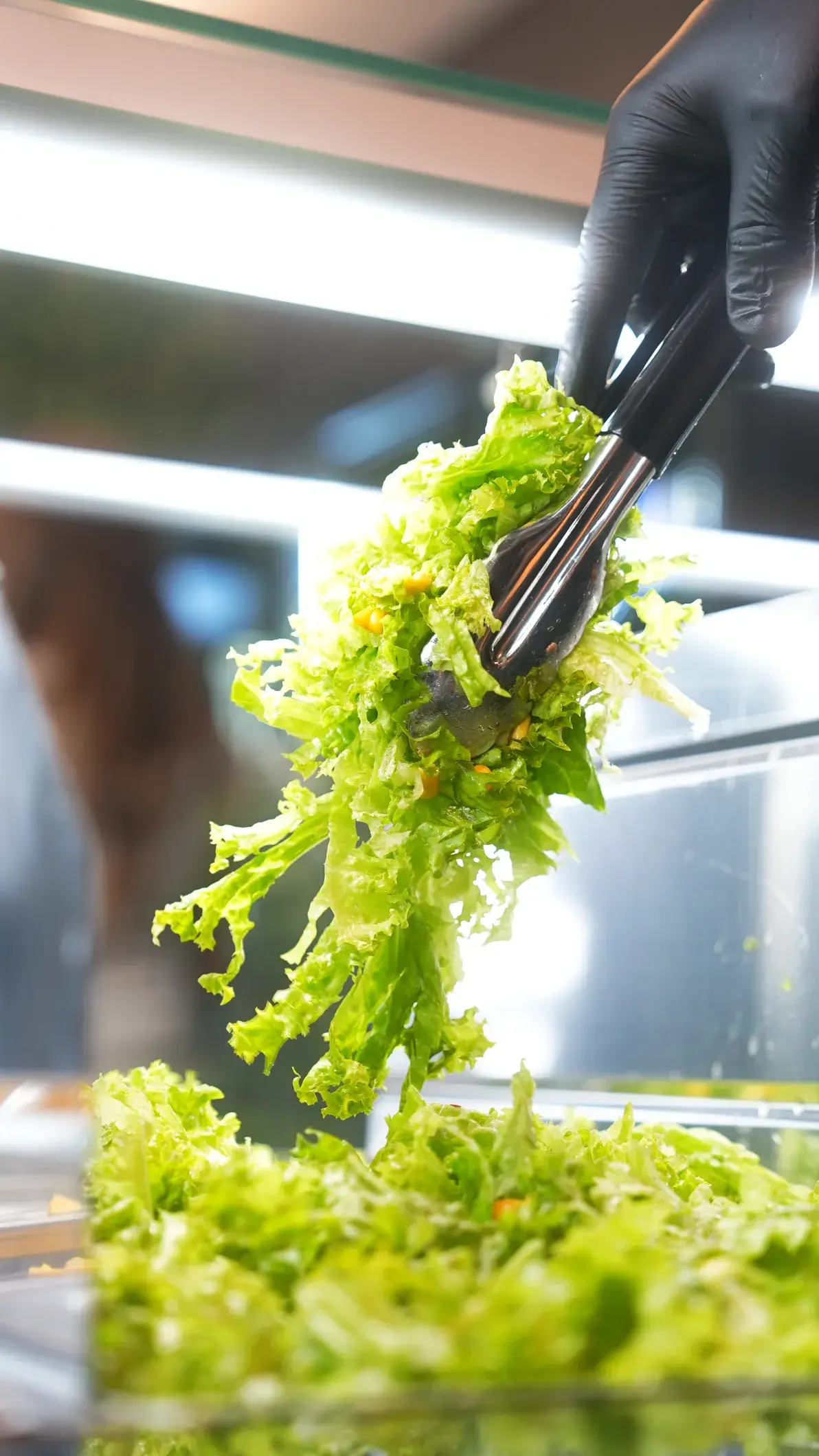 Frischer Salat wird mit der Zange aufgenommen